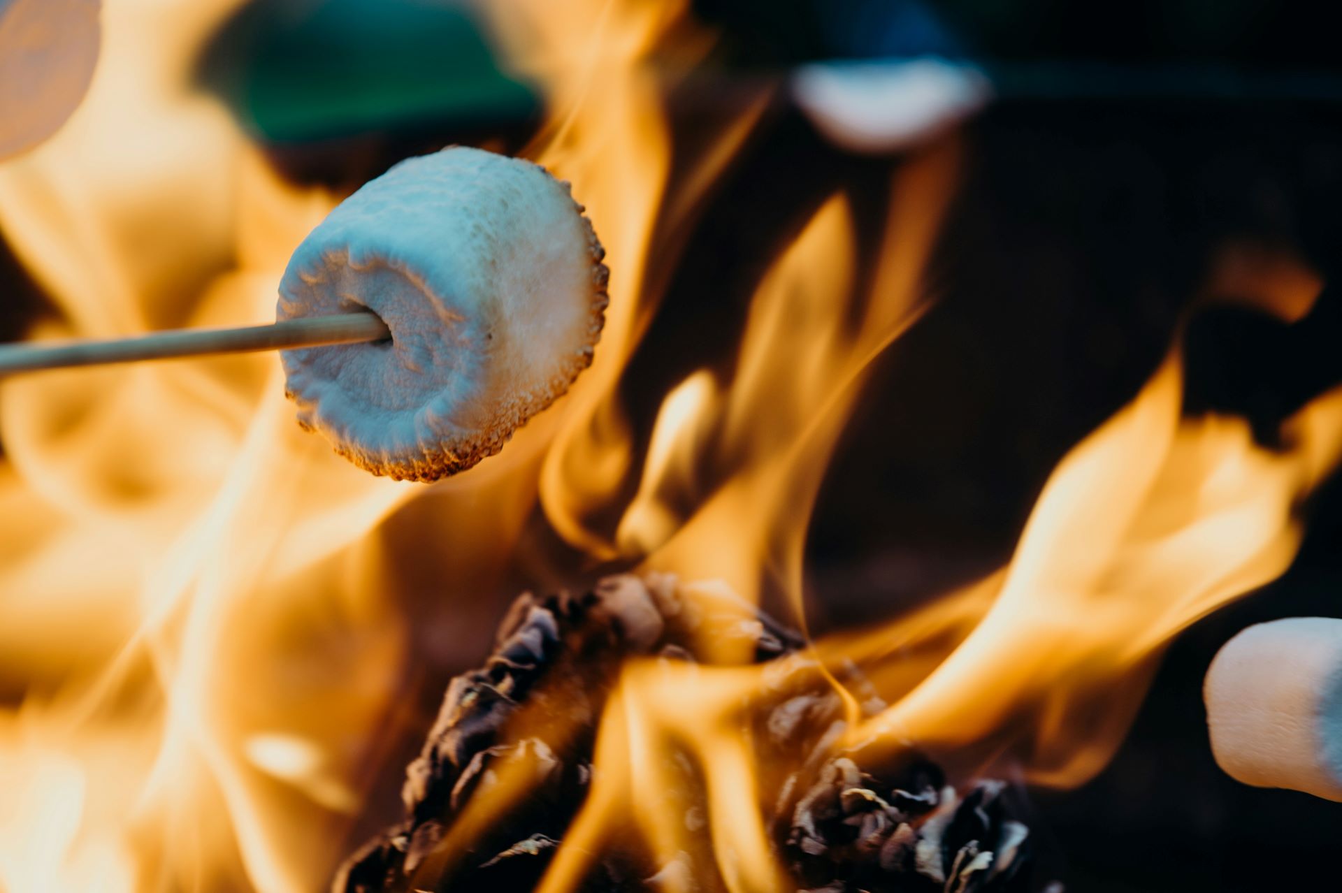 Nahaufnahme eines gerösteten Marshmallows über einer offenen Flamme, ideal für Outdoor-Abende am Lagerfeuer