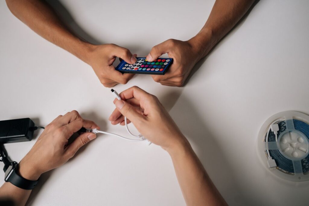 Zwei Personen verbinden LED-Leiste mit einem LED Controller und Fernbedienung zur Einrichtung eines Lichtsystems