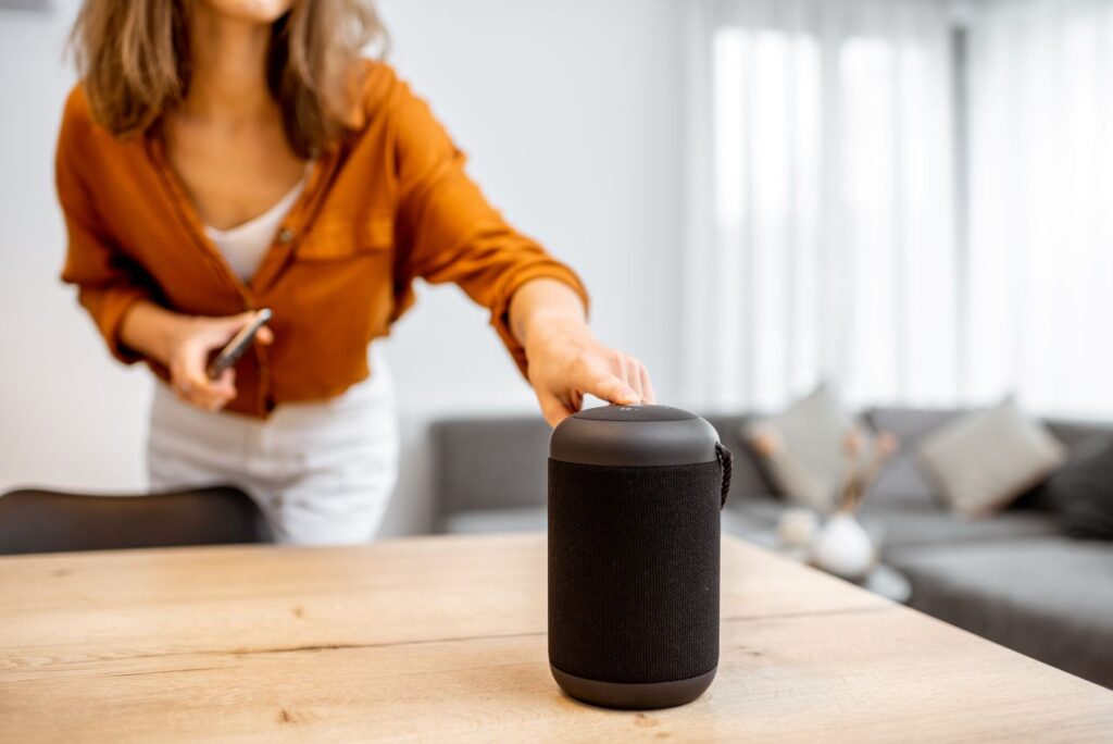 Frau steuert kabellosen Lautsprecher im Wohnzimmer als Teil eines Smart-Home-Systems mit LED Controller