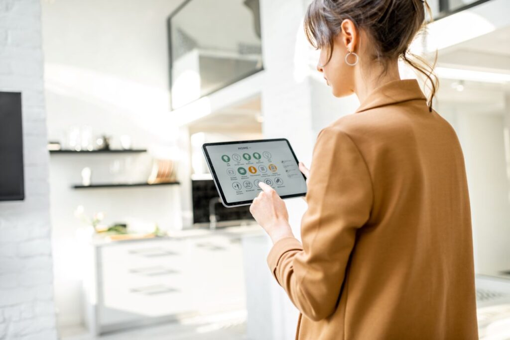 Frau bedient ein Smart-Home-System mit Tablet zur Steuerung von Licht, Heizung und LED Controller in moderner Kueche
