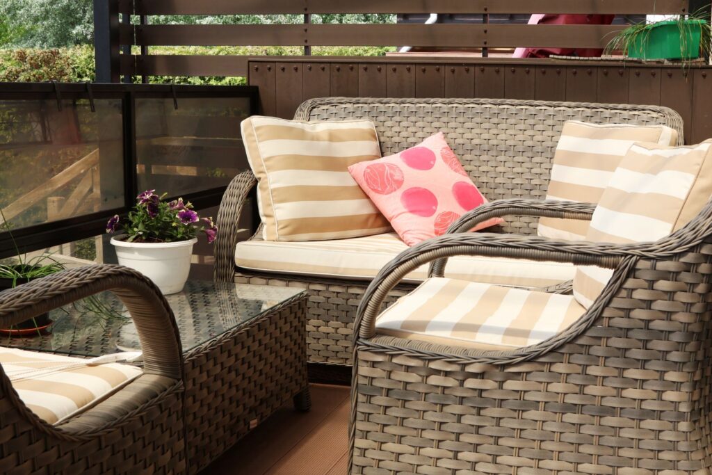 Gemuetliche Terrasse mit Rattanmoebeln und Kissen in einem gepflegten Gartenbereich in Koeln